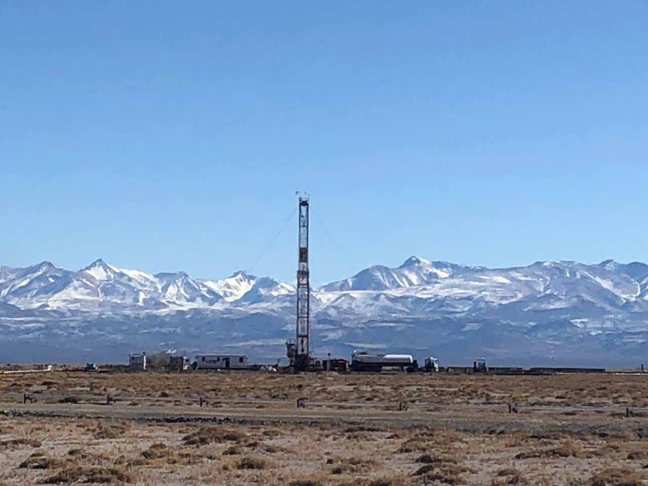 Equipo de perforación en la meseta neuquina con la cordillera nevada de fondo